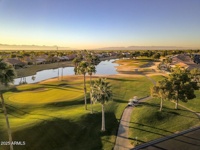 aerial view at dusk with a residential view, a water view, and golf course view