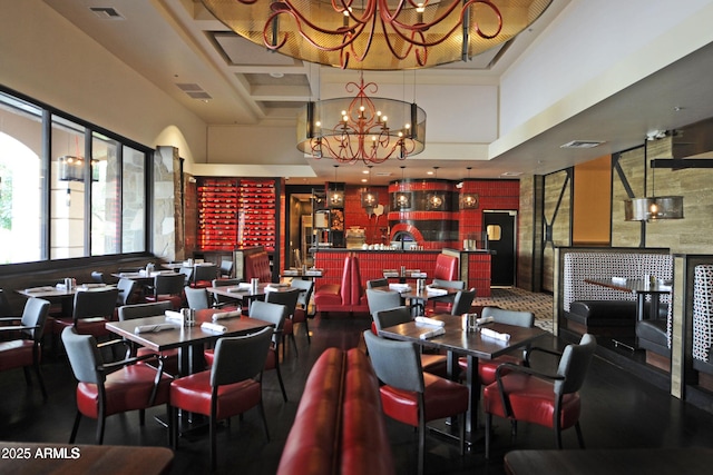 dining area featuring a towering ceiling, visible vents, and a notable chandelier