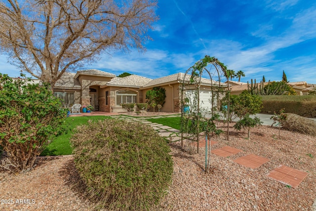 back of property featuring stone siding, an attached garage, a tile roof, and stucco siding