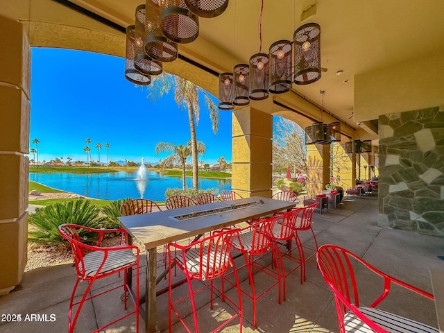 view of patio / terrace featuring a water view, a ceiling fan, and an outdoor bar