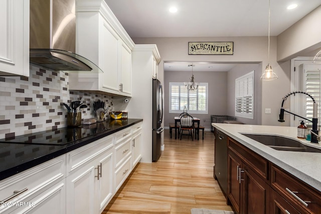 kitchen with decorative light fixtures, sink, wall chimney range hood, and black appliances