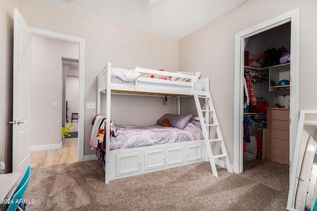 bedroom featuring a walk in closet, light colored carpet, and a closet