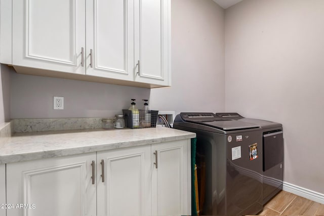 laundry room with cabinets, washer and dryer, and light hardwood / wood-style flooring