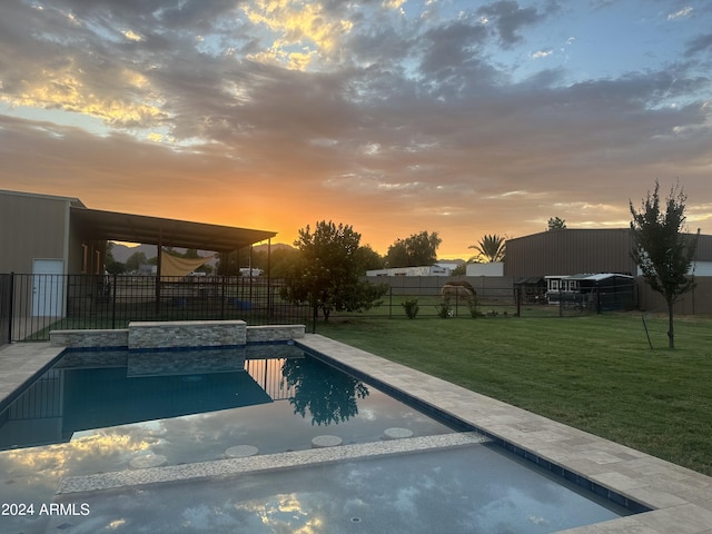 pool at dusk featuring a yard