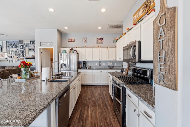 kitchen with sink, white cabinetry, appliances with stainless steel finishes, dark stone countertops, and dark hardwood / wood-style flooring