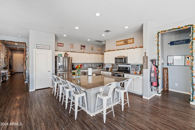 kitchen featuring a center island, dark wood-type flooring, a breakfast bar area, white cabinets, and appliances with stainless steel finishes