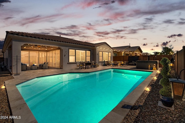 pool at dusk with a patio area