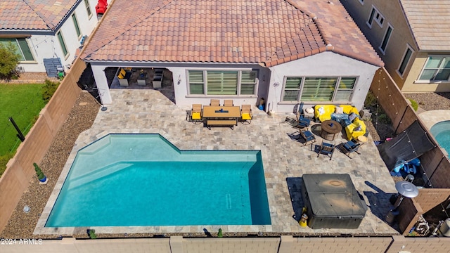 rear view of property with a fenced in pool and a patio