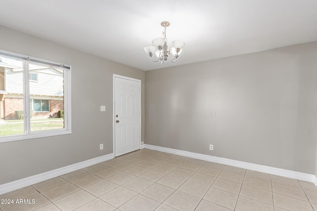 tiled spare room with a chandelier