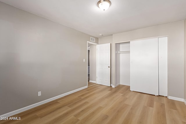 unfurnished bedroom with a closet and light hardwood / wood-style floors