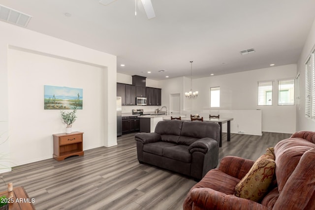 living room featuring ceiling fan with notable chandelier, sink, and hardwood / wood-style floors