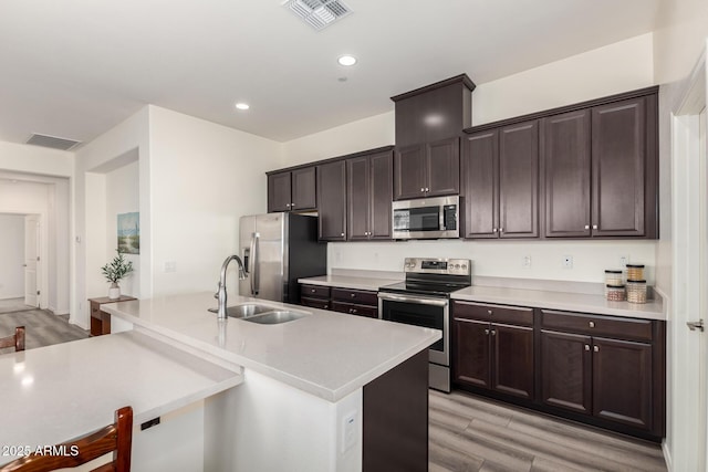 kitchen featuring dark brown cabinetry, sink, light hardwood / wood-style flooring, and appliances with stainless steel finishes