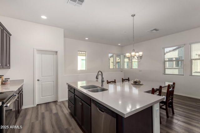 kitchen with sink, stainless steel appliances, dark hardwood / wood-style floors, a center island with sink, and decorative light fixtures