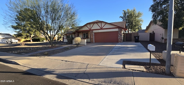 english style home featuring driveway, brick siding, an attached garage, and a gate