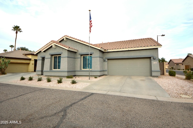 view of front of home with a garage, driveway, a tiled roof, and stucco siding