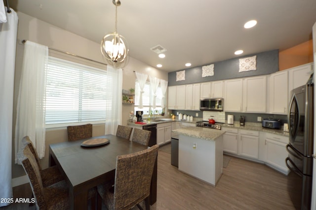 kitchen with stainless steel appliances, wood finished floors, a center island, and white cabinets