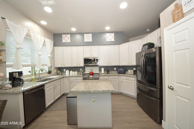 kitchen with recessed lighting, a sink, white cabinets, appliances with stainless steel finishes, and a center island