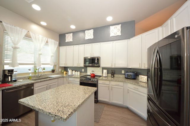 kitchen with stainless steel appliances, recessed lighting, white cabinetry, a sink, and a kitchen island