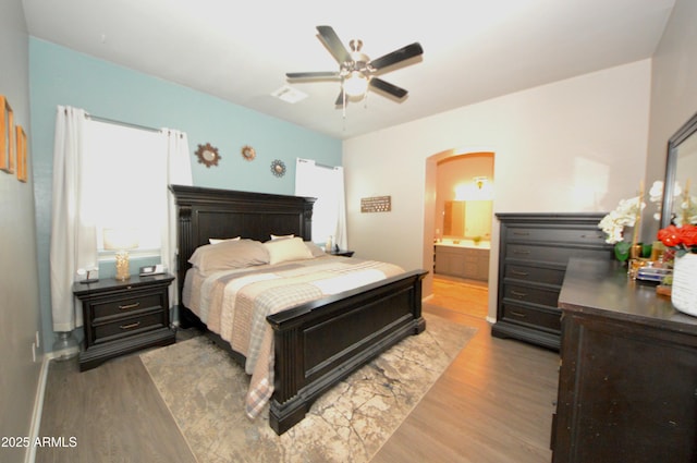 bedroom featuring arched walkways, visible vents, wood finished floors, and a ceiling fan