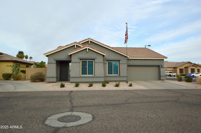 view of front of property featuring an attached garage, driveway, a tiled roof, and stucco siding