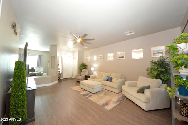 living area featuring visible vents, ceiling fan, baseboards, and wood finished floors