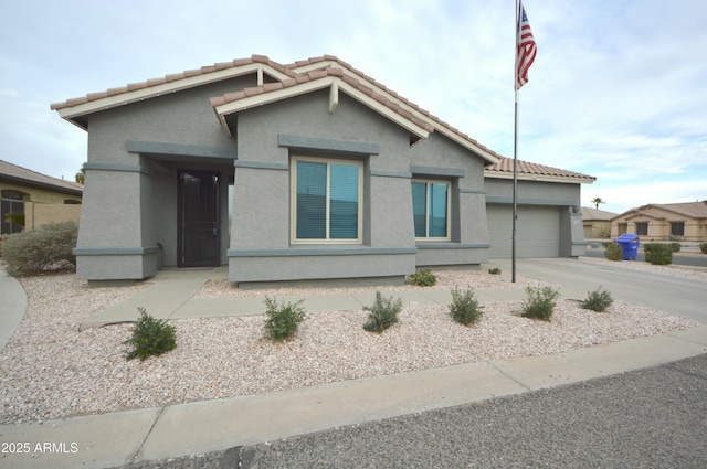 view of front of house featuring concrete driveway, a tile roof, an attached garage, and stucco siding