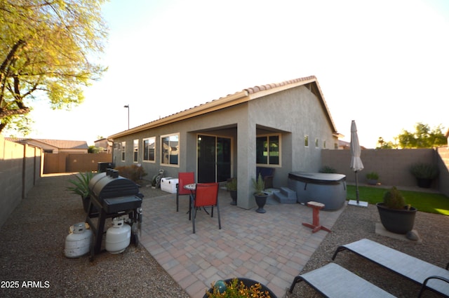 back of property with a fenced backyard, a patio, a hot tub, and stucco siding