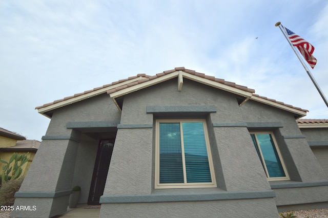 exterior space with a tile roof and stucco siding