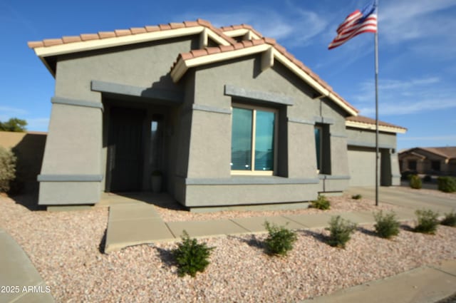 view of home's exterior featuring a garage, concrete driveway, a tiled roof, and stucco siding