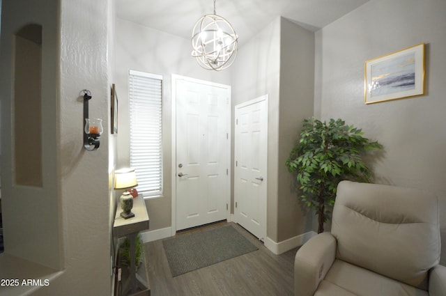 foyer entrance featuring a notable chandelier, baseboards, and wood finished floors