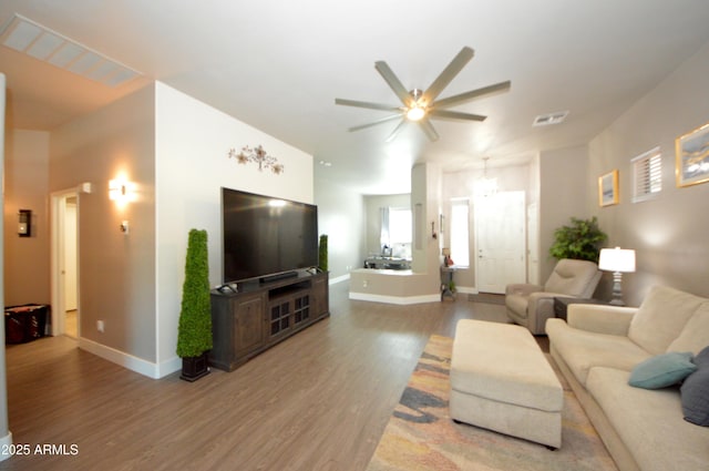 living area with a ceiling fan, wood finished floors, visible vents, and baseboards