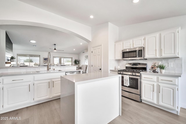 kitchen with lofted ceiling, tasteful backsplash, arched walkways, and stainless steel appliances