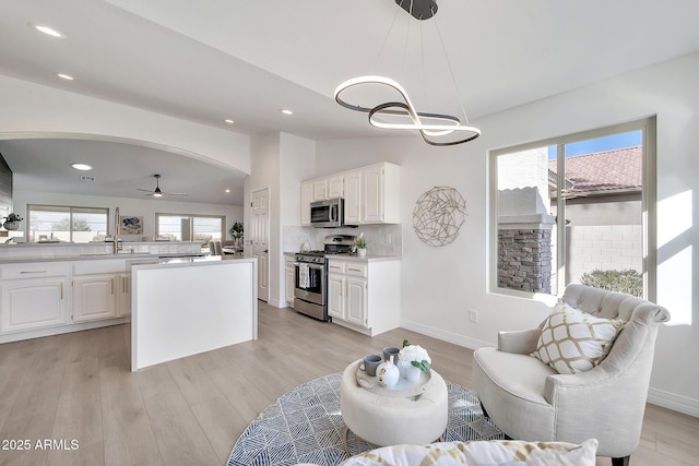 living room with light wood-type flooring, lofted ceiling, baseboards, and recessed lighting