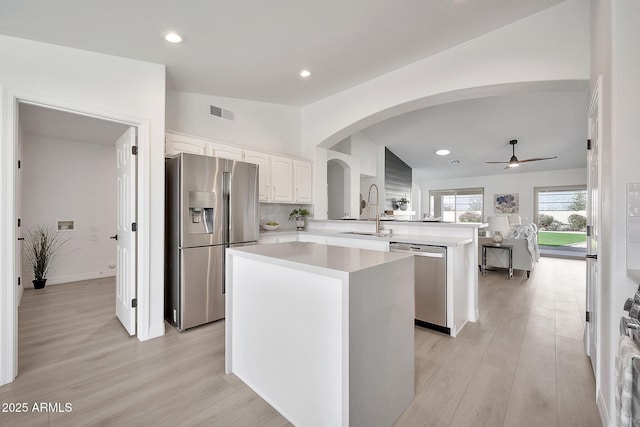 kitchen with appliances with stainless steel finishes, a center island, a peninsula, vaulted ceiling, and a sink