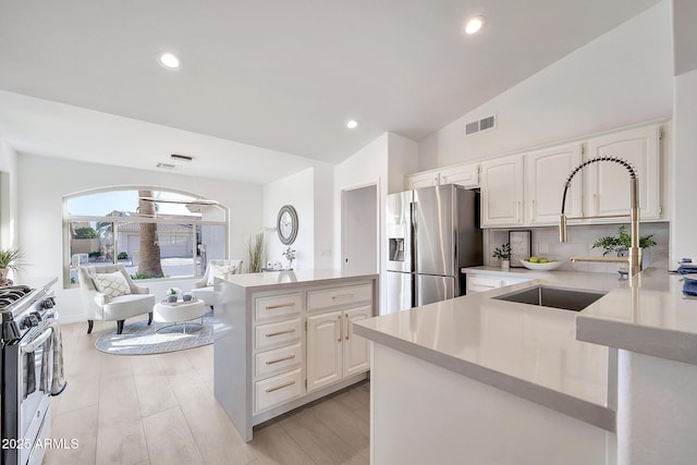 kitchen featuring a sink, visible vents, vaulted ceiling, light countertops, and appliances with stainless steel finishes