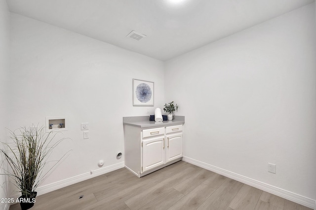 laundry area featuring hookup for a washing machine, visible vents, cabinet space, light wood-style flooring, and baseboards