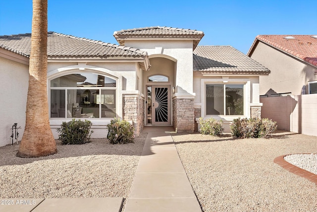 exterior space with stone siding, fence, stucco siding, and a tiled roof