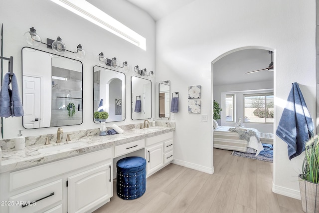 bathroom featuring ceiling fan, double vanity, wood finished floors, and a sink