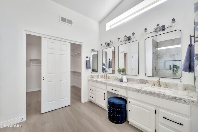 full bath featuring a spacious closet, a stall shower, a sink, and visible vents