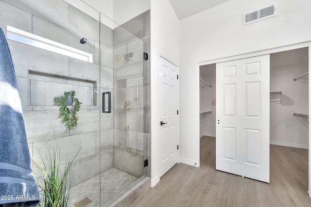 full bath with a stall shower, baseboards, visible vents, and wood finished floors