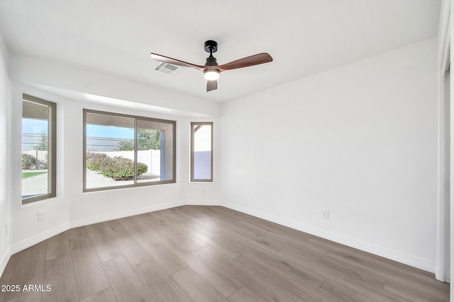 unfurnished room with dark wood-style floors, visible vents, baseboards, and a ceiling fan