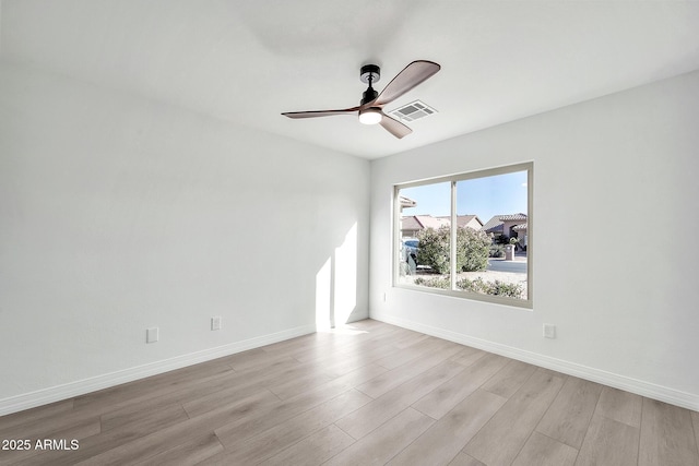 empty room featuring ceiling fan, light wood-style flooring, visible vents, and baseboards