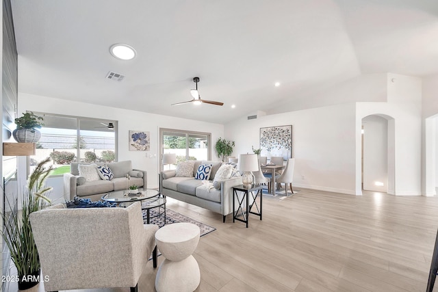 living room featuring arched walkways, vaulted ceiling, light wood finished floors, and ceiling fan