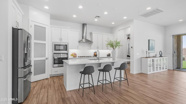 8140 E June St, Mesa, AZ 85207 - kitchen featuring appliances with stainless steel finishes, wall chimney exhaust hood, light countertops, white cabinets, and light wood finished floors