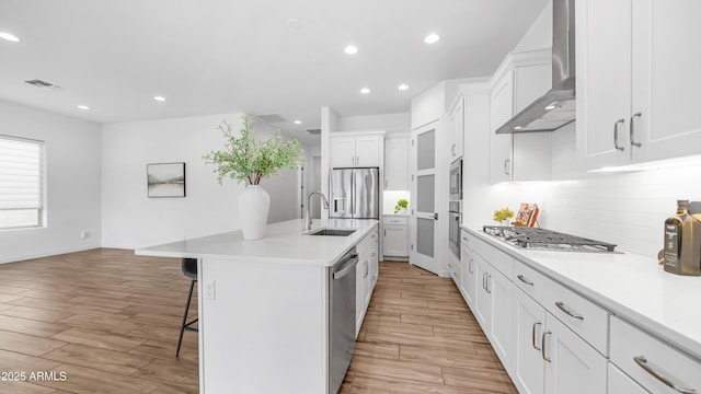 8140 E June St, Mesa, AZ 85207 - kitchen featuring wall chimney exhaust hood, stainless steel appliances, a kitchen breakfast bar, light wood-style floors, and recessed lighting