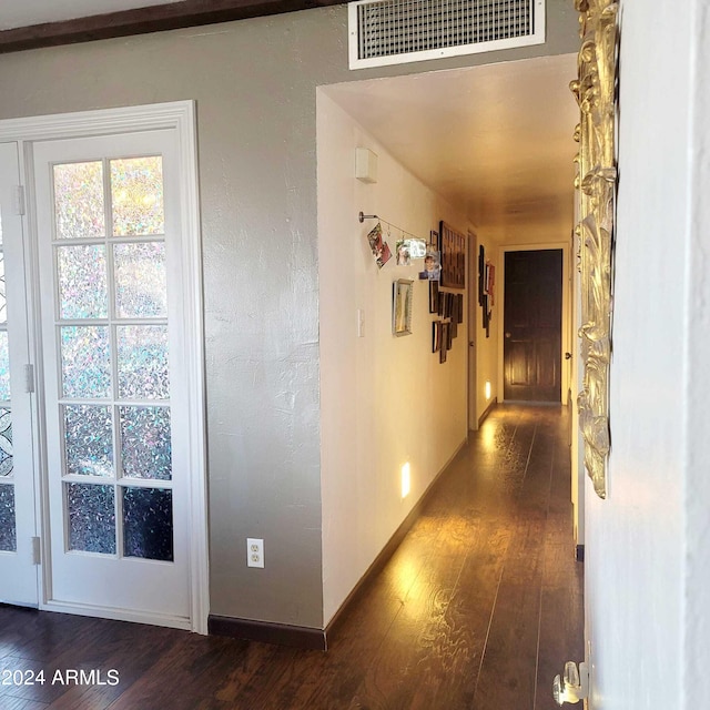 hall with dark wood finished floors, visible vents, and baseboards