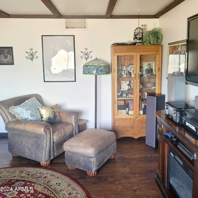 sitting room with visible vents, beamed ceiling, and dark wood-style floors