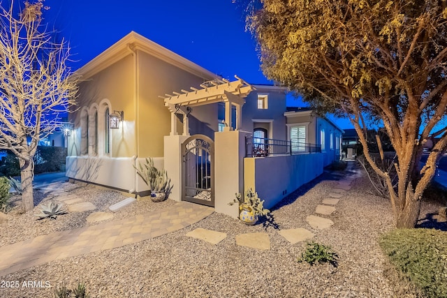 view of property exterior featuring a fenced front yard, stucco siding, a gate, and a pergola