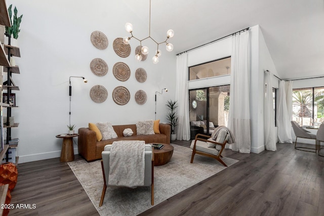 interior space with an inviting chandelier, high vaulted ceiling, wood finished floors, and baseboards