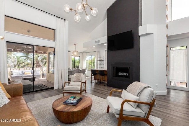 living room with a chandelier, visible vents, wood finished floors, and high vaulted ceiling